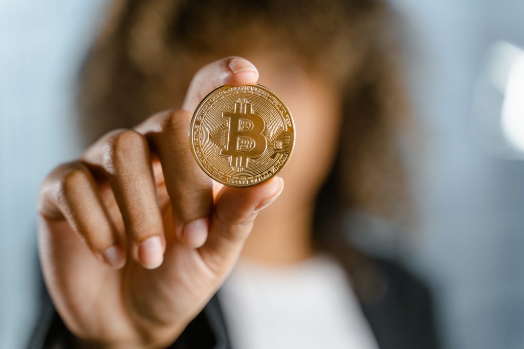 Jeune femme brandissant une pièce de bitcoin